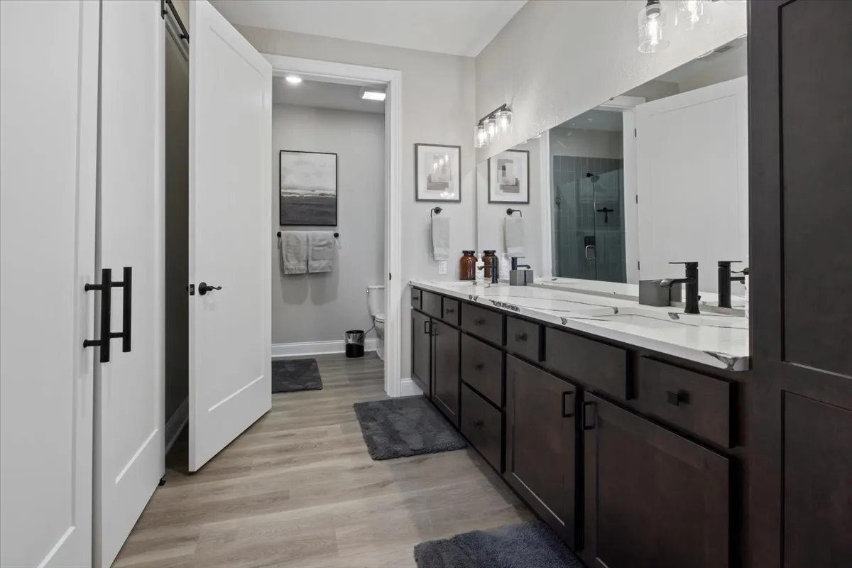 A spa-like bathroom with a double vanity, large mirror, and tasteful artwork on the wall. The tranquil mood and elegant finishes create an inviting space for personal grooming and relaxation.
