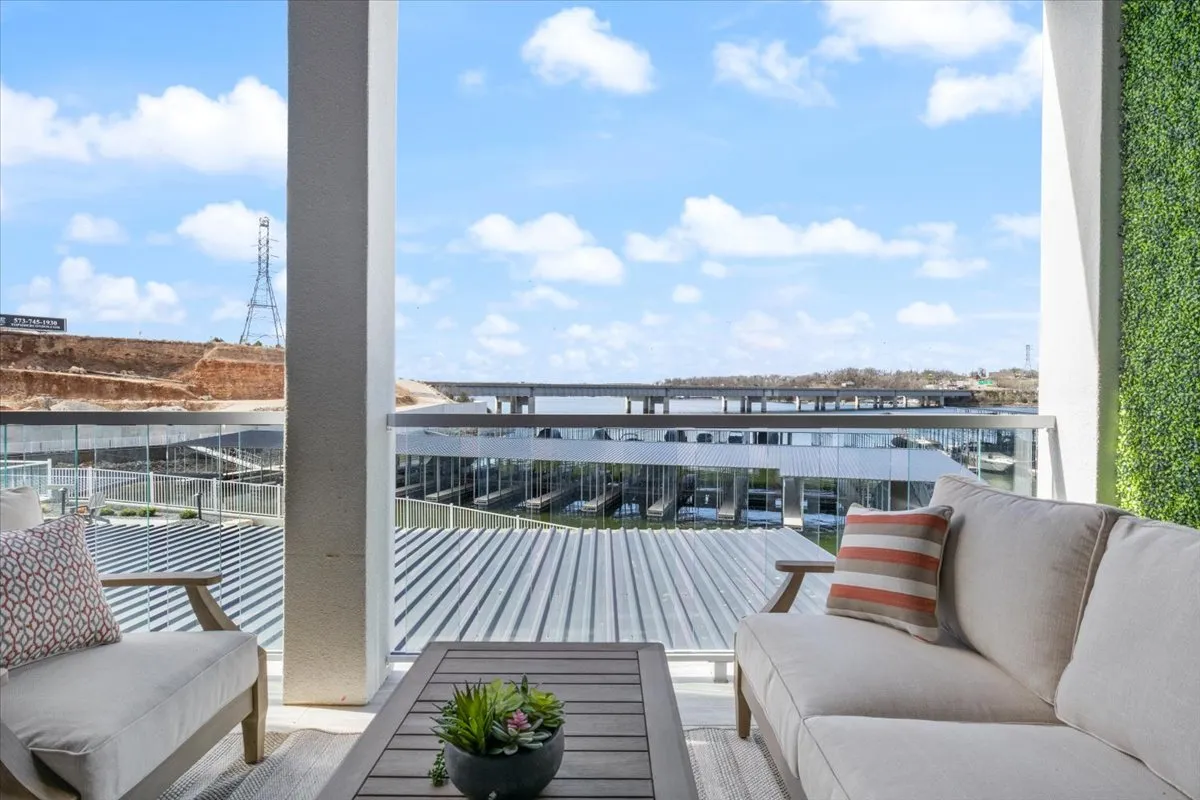 A spacious outdoor seating area overlooking the water, featuring a comfortable arrangement for relaxing and entertaining. Succulents and decorative planters add a touch of greenery, while a bridge in the background enhances the lakeside atmosphere. The area is perfectly oriented to capture tranquil water views.