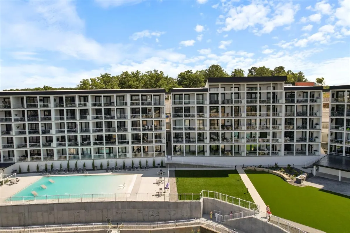 An exterior shot showing a swimming pool, balconies, and a lush green lawn. The green space appears spacious and well-maintained, offering an appealing area for relaxation or light recreation.