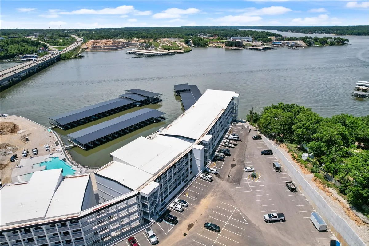 A wide shot of the waterfront shows the marina docks, the lake, and adjacent hotel and parking, with boats visible and open space for walking and relaxation. The image captures both the relaxing and active aspects of lakeside living, reinforcing the community's connection to the water.