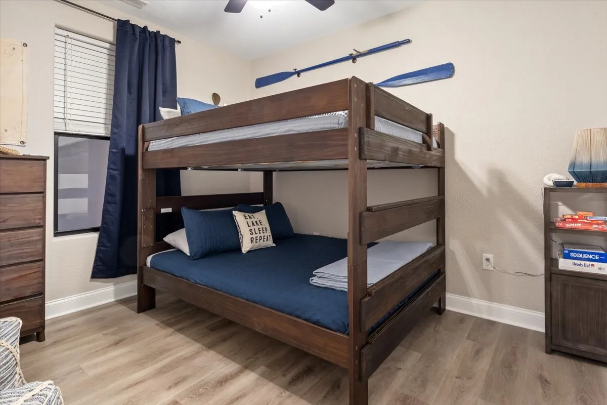 A playful bunk room decorated with blue bedding, decorative paddles on the wall, and a sturdy bunk bed. The room feels inviting and fun, designed with both children and adventurous adults in mind.