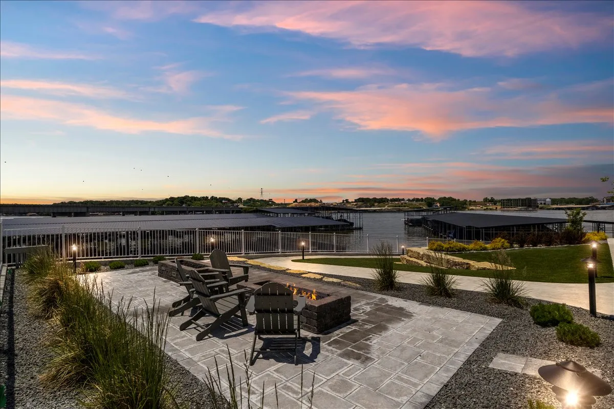 This exterior shot features a communal firepit surrounded by cozy outdoor seating, all set along the waterfront. The firepit glows against the evening sky, inviting guests to gather, share stories, and enjoy sunset views over the lake.